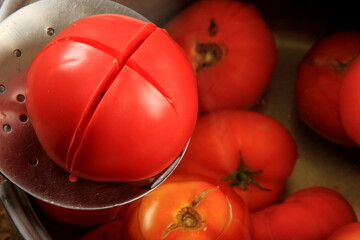 Red ripe tomatoes in a pot of hot water. Boiled Tomatoes. tomatoes poached in boiling water