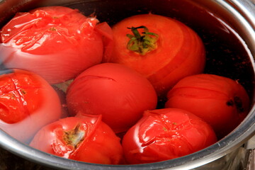 Red ripe tomatoes in a pot of hot water. Boiled Tomatoes. tomatoes poached in boiling water