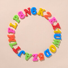 Alphabet letters and numbers in a circle as a concept for back to cheekbones. Pastel education idea.