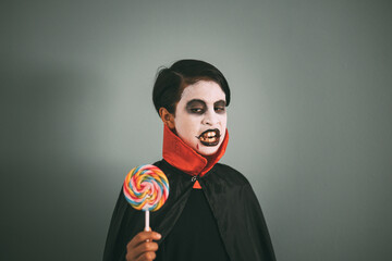 Girl with Dracula make-up plays with a lollipop alluding to the candies and sweets given out on...