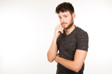 Caucasian young man with dark hair with beard and serious expression looking at camera