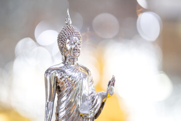 Silver shining Buddha statue with gold and silver background.