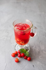 Fresh cherry fruit juice compote in a glass with ice in the shape of a heart on a light background.with mint.