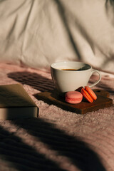 Fototapeta na wymiar coffee, macaroons and a book on the bed