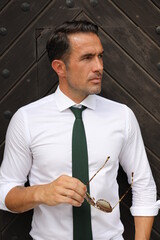 Fototapeta Bardzo przystojny, elegancki mężczyzna w białej koszuli i zielonym krawacie i okularach przeciwsłonecznych. obraz