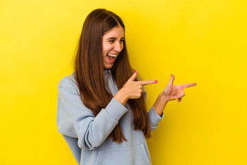Fototapeta premium Young caucasian woman isolated on yellow background points with thumb finger away, laughing and carefree.