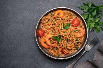 Spaghetti with shrimps in tomato cream sauce on black background