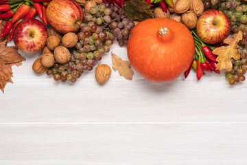 Set of autumn vegetables, fruits, nuts and leaves on white wooden background