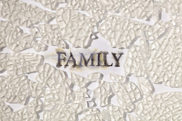 The text "FAMILY" on the broken glass and white background. Concept of conflict or loneliness. 