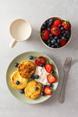 Cottage Cheese Pancake with strawberries, blueberries and sour cream, mug with milk and fresh berries, delicious breakfast, top view