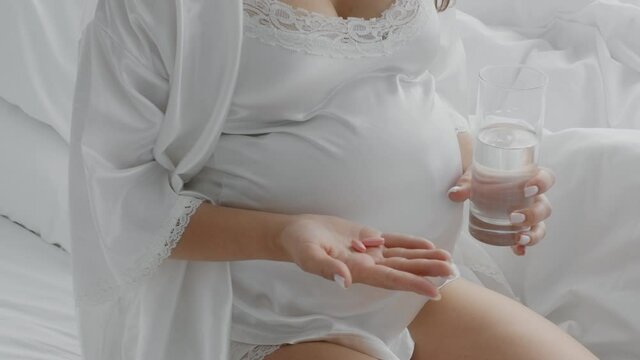 Prenatal Supplements. Unrecognizable Pregnant Woman Holding Vitamin Pills And Glass Of Water