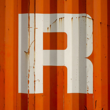 Grunge single letter R on an orange corrugated enameled metal background