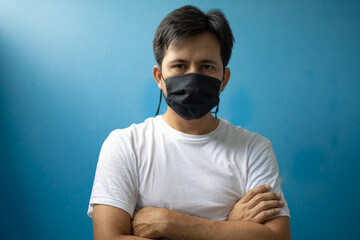 portrait young asian man wear a mask standing on a blue background
