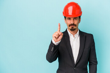 Young architect caucasian man isolated on blue background showing number one with finger.