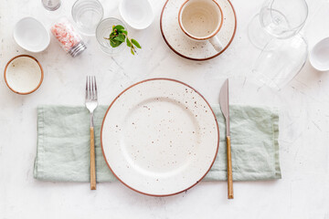 Tableware set with empty plate with dishware and glasses on napkin