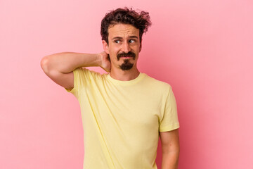 Young caucasian man isolated on pink background touching back of head, thinking and making a choice.