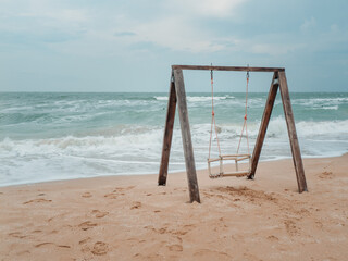 Wooden swing on the shores of the raging sea.