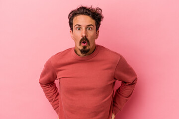 Young caucasian man isolated on pink background being shocked because of something she has seen.