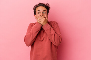 Young caucasian man isolated on pink background thoughtful looking to a copy space covering mouth with hand.