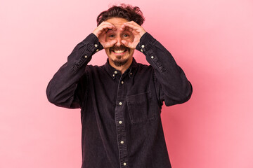 Obraz premium Young caucasian man isolated on pink background showing okay sign over eyes
