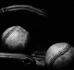 Dark moody baseballs in glove used from game play during sports season.
