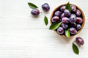 Ripe garden plums in bowl. Cherry fruit with leaves. Top view