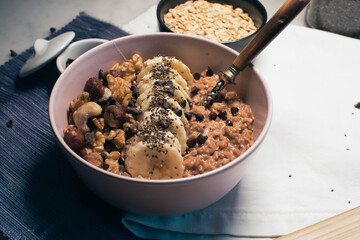 Bowl of oatmeal porridge with banana and nuts. Top view. Healthy vegan breakfast