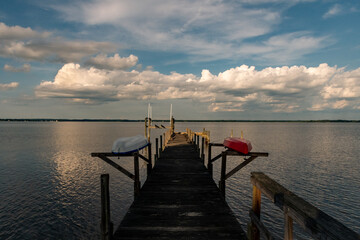Obraz premium Dock on the river with Kayaks and summer clouds during our summer vacation
