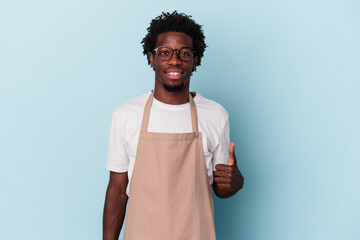 Young african american store clerk isolated on blue background smiling and raising thumb up