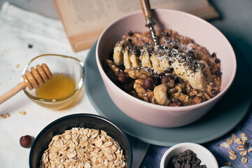 Bowl of oatmeal porridge with banana and nuts. Top view. Healthy vegan breakfast - obrazy, fototapety, plakaty