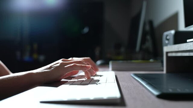 woman working on computer at home using keyboard print documents Close-up shot on a desk, backlit. Hand-held shooting