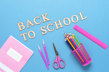 Back to school. Stationery on a blue paper background. Colored pencils, pens, ruler, scissors and a notebook. Top view, flat lay.
