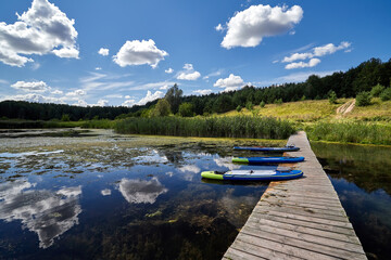 Obraz premium Sup boards stand from a wooden bridge on the lake.
