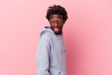 Young african american man isolated on pink background looks aside smiling, cheerful and pleasant.