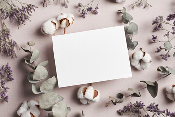 Invitation or greeting card mockup with eucalyptus twigs and cotton plant flowers decorations