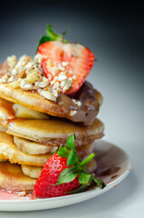 Pancakes stacked with bananas, strawberries and nuts, topped with chocolate and strawberry sauce