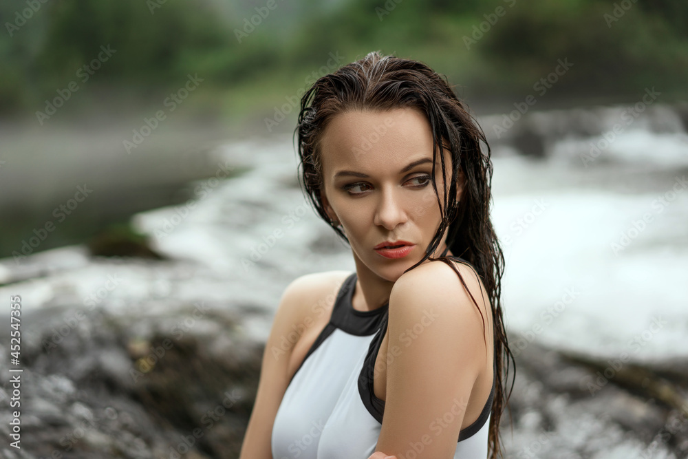 Sticker Sexy Caucasian brunette woman with wet hair posing in a white swimsuit on the beach