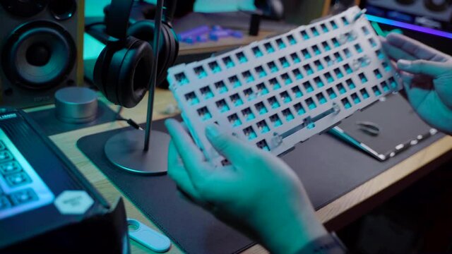 A footage of a man assemble a DIY premium custom keyboard build kit with full alluminium base and bright RGB LED Colors
