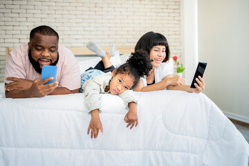 A 5-year-old African-American girl, showing up in a bad mood because her parents are not interested, and using mobile phones all the time, to family and social media concept.