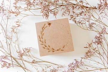Round frame made of lilac flowers on white background with wood gift box. Flat lay, top view.