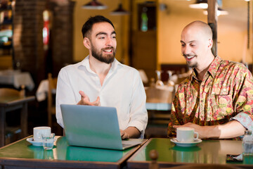Fototapeta premium Two people using a laptop on a meeting at a coffee shop.