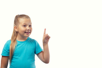 A little girl in a blue T-shirt raised her index finger up. Isolated on a white background. Place for your text