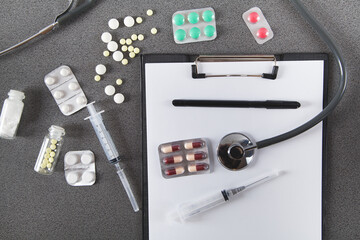  Doctors desk. Stethoscope, notebook and  pills, on gray background. Concept of medicine.