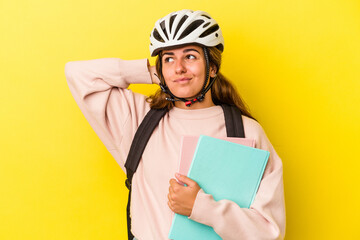 Young caucasian student woman wearing a bike helmet isolated on yellow background  touching back of head, thinking and making a choice.