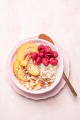 Porridge oatmeal with raspberries, peaches and nuts for breakfast. Healthy vegetarian food concept.