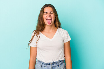 Young caucasian woman isolated on blue background  funny and friendly sticking out tongue.