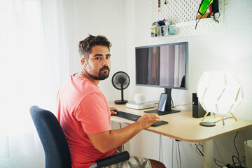 Hispanic bearded man using computer on desk looking at camera