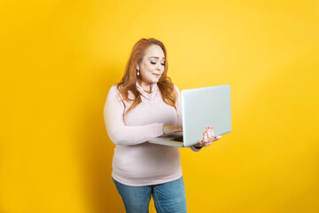 white mature business woman working on laptop on isolated yellow background