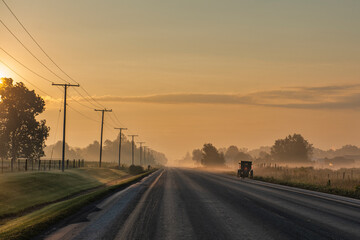 The golden light of morning on rural Indiana road with Amish Buggy.