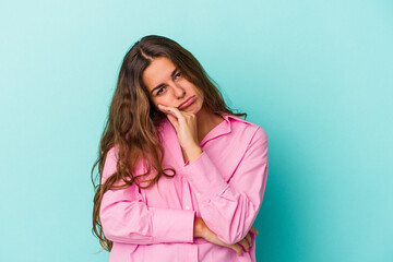 Young caucasian woman isolated on blue background  tired of a repetitive task.